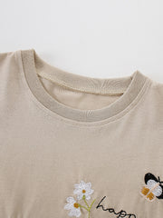 Beige cotton tee with embroidered daisies, butterfly, and "happ" text detail.