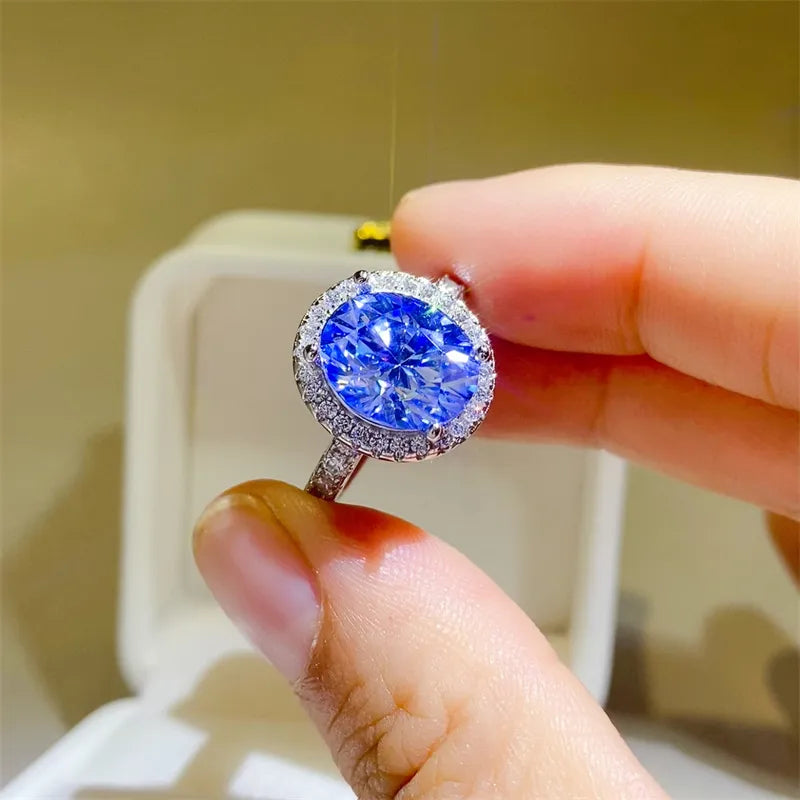 Silver halo engagement ring with a bright blue oval moissanite center stone.