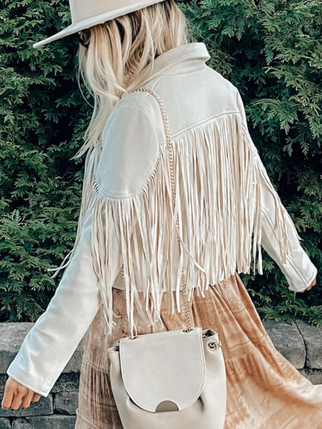 Beige cropped jacket with fringe detailing and open front, styled with a crossbody bag.