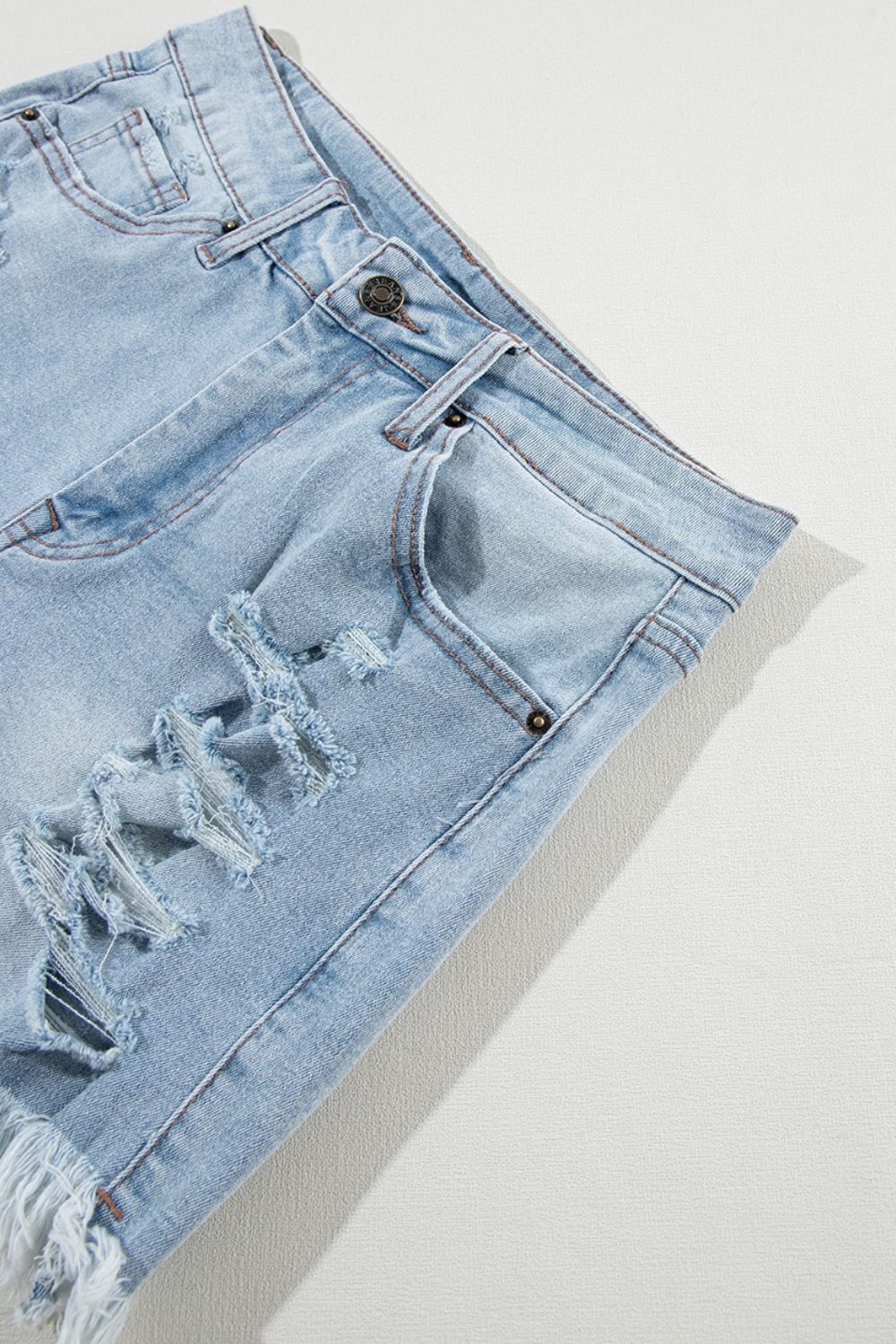 Light blue distressed denim cutoff shorts with frayed hem and ripped details.