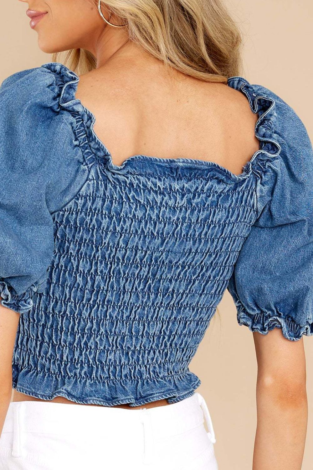 Smocked denim crop top with ruffled sleeves and square neckline in medium wash.
