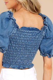 Smocked denim crop top with ruffled sleeves and square neckline in medium wash.
