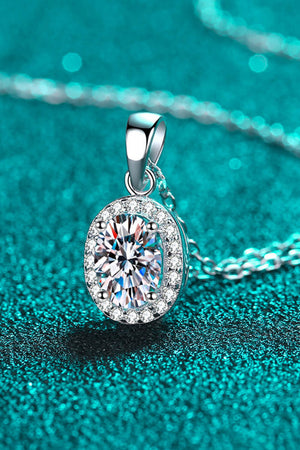 Silver halo moissanite pendant necklace with oval cut center stone and diamond accent halo on sterling silver chain.