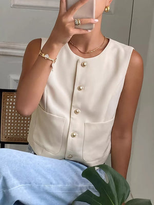 Cream button-down sleeveless vest with crew neck, gold buttons, and pocket details.