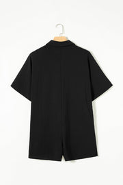 Black oversized shirt romper with short sleeves and textured fabric.