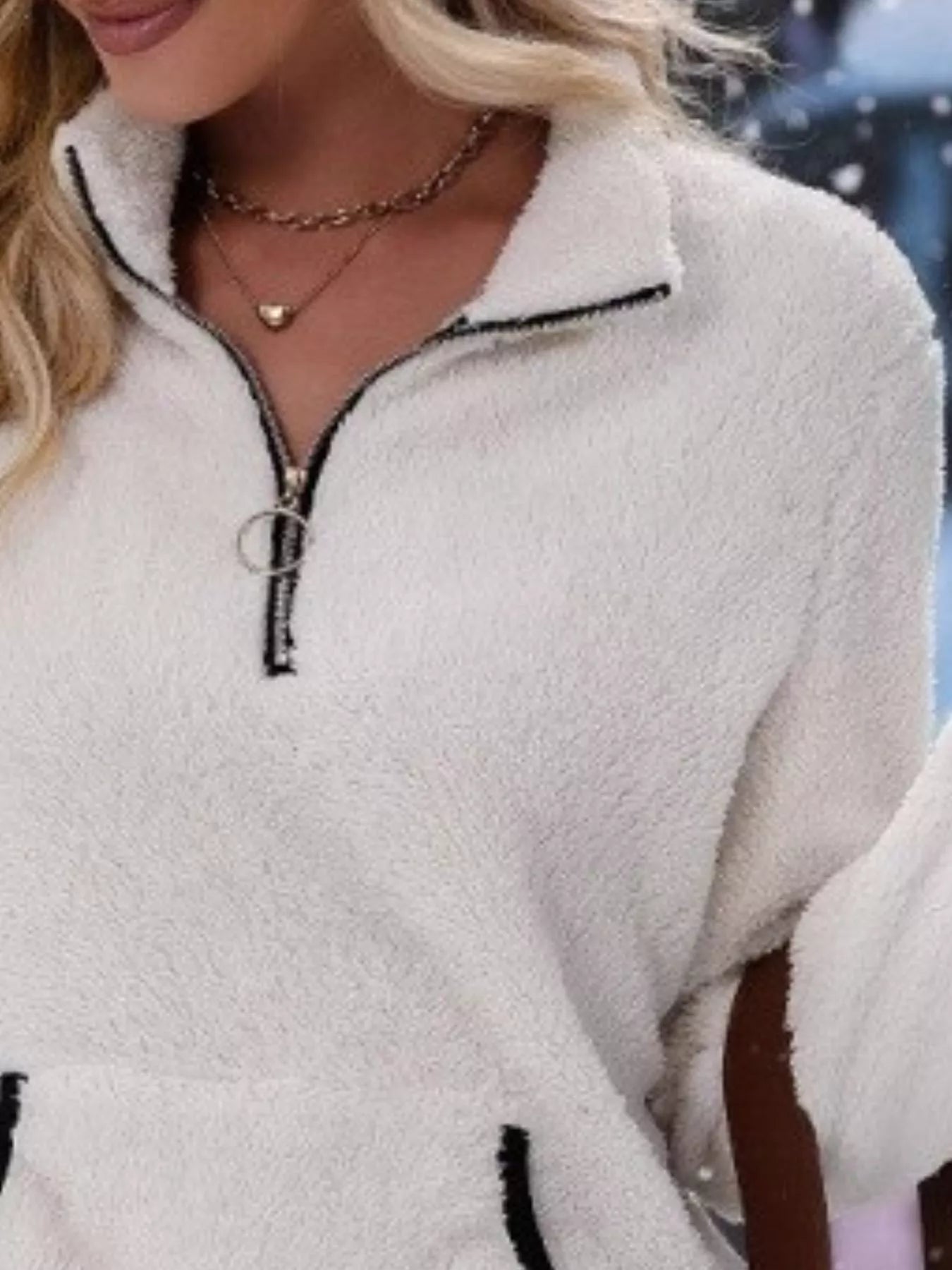 White fleece quarter zip pullover with black trim and ring zipper detail.
