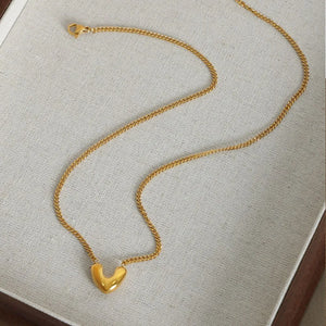 Gold heart charm necklace with a delicate curb chain, perfect for everyday wear.