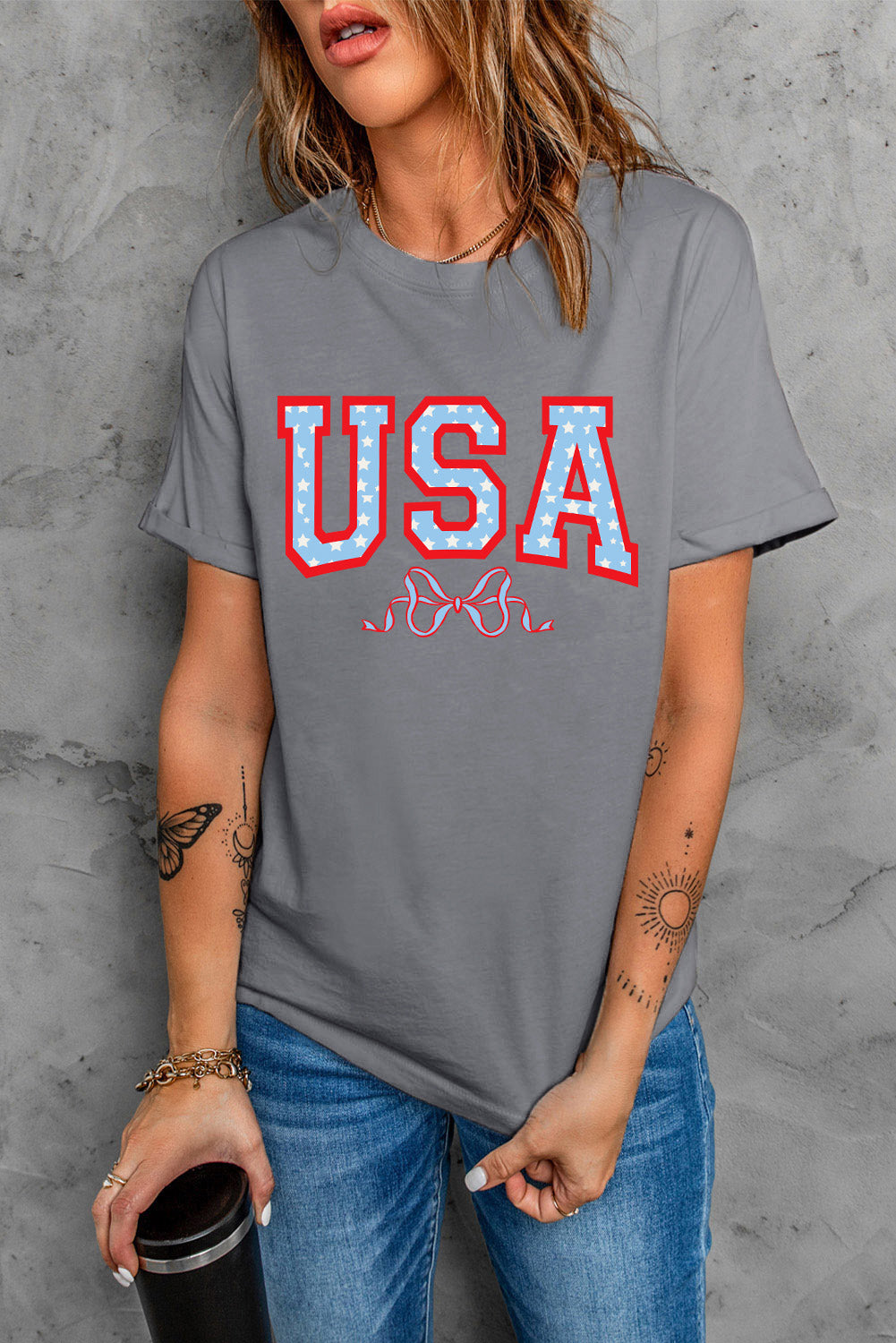 Dark gray cotton tee with rolled sleeves and a red and blue USA graphic with stars and a bow detail.