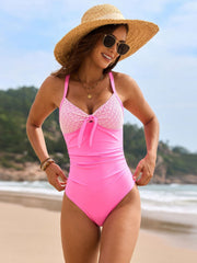 Fuchsia pink one-piece swimsuit with textured panel bust and bow detail.