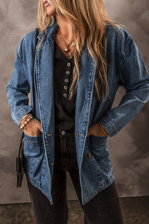 Medium wash denim double-breasted blazer with button front and flap pockets.