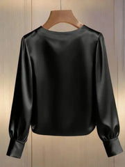 Black satin blouse with round neck, long sleeves, and pearl trim detail.