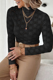 Black floral lace turtleneck top with long sleeves, styled with layered necklaces and gold jewelry.