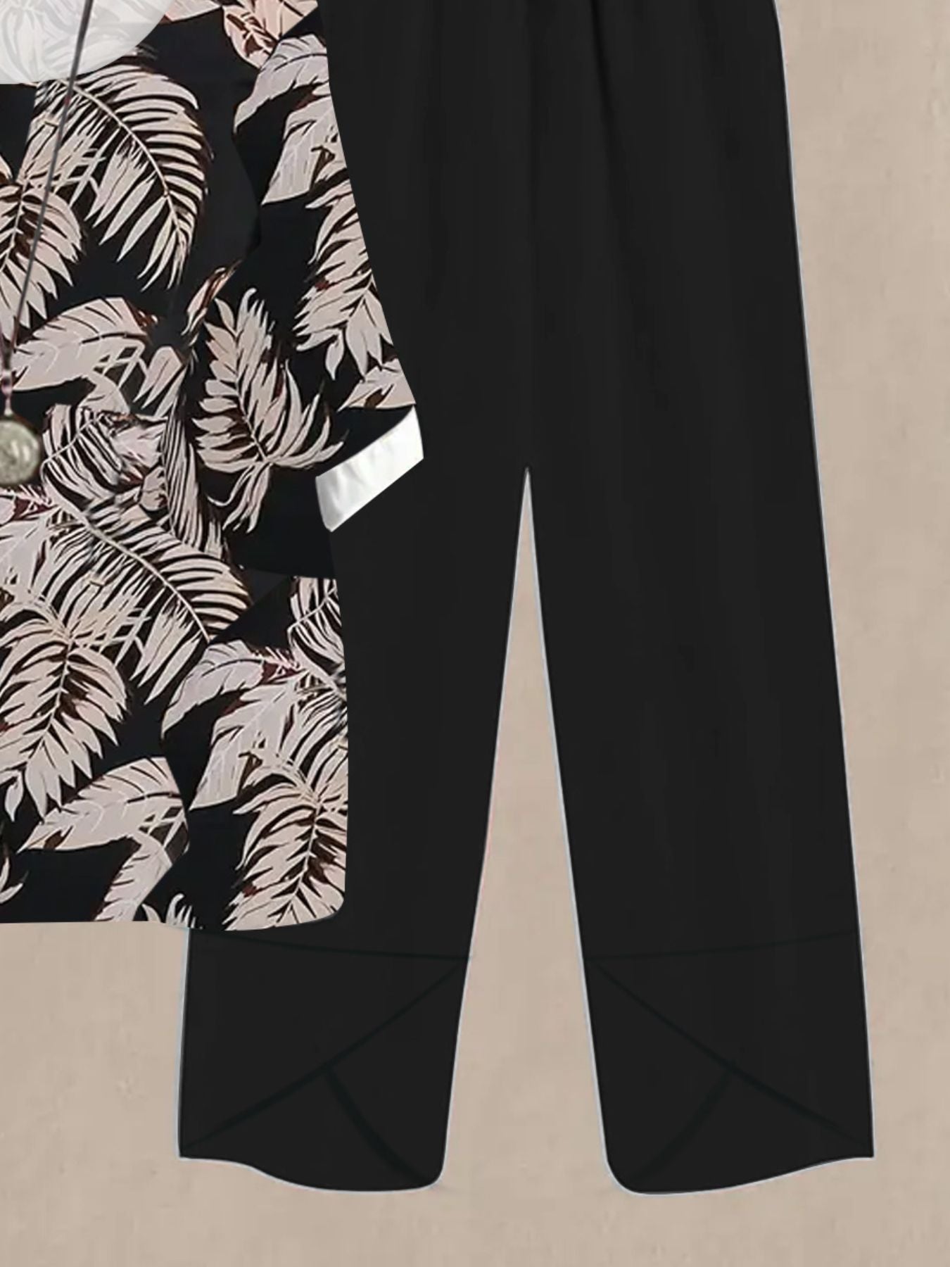 Black floral print half sleeve top with white cuffs paired with black wide leg pants.