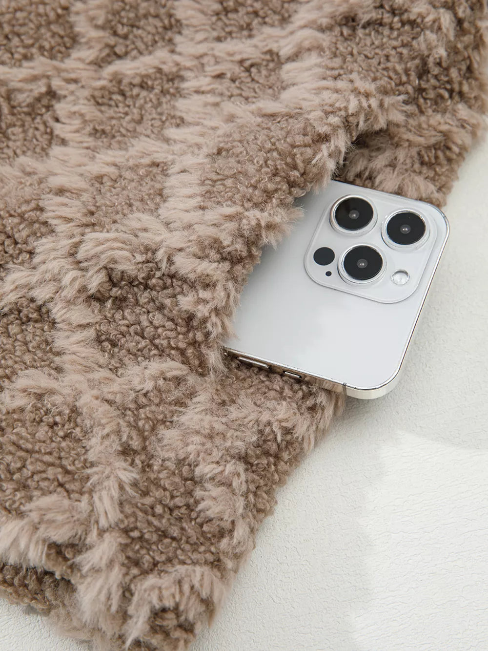 Textured sherpa fleece jacket in brown with a diamond pattern, showing a pocket holding a smartphone.