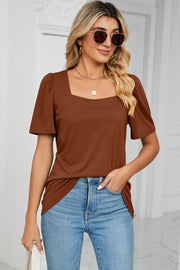 Caramel tee with square neck and sculpted puff sleeves, styled with jeans.