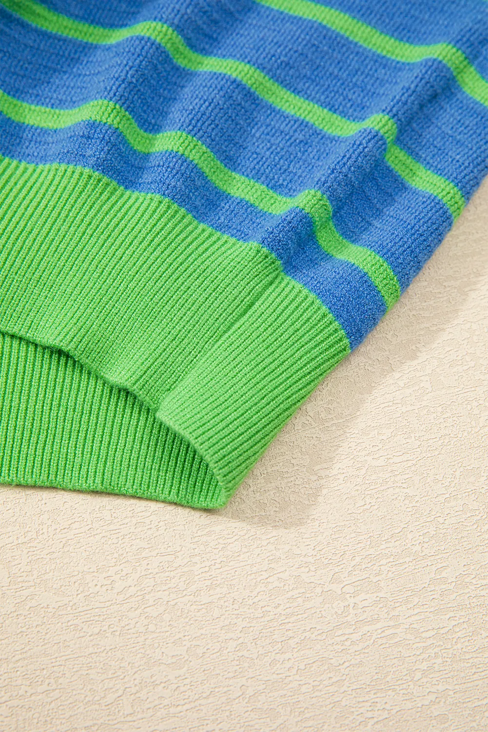 Waffle knit sweater with blue and green stripes and ribbed cuffs.