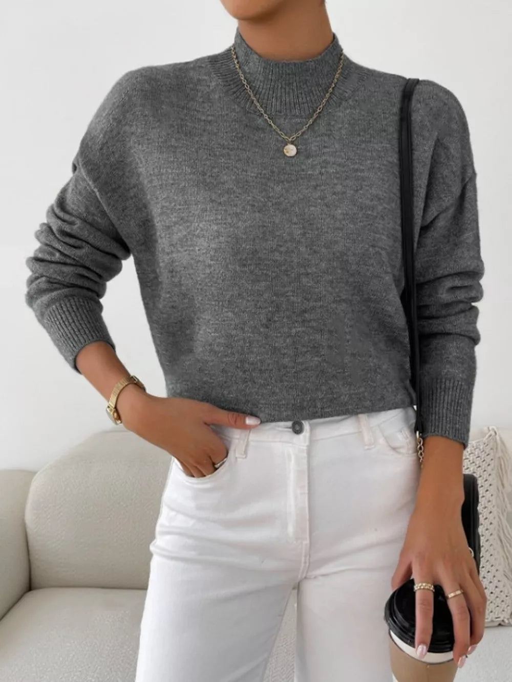 Gray acrylic mock neck sweater with dropped shoulders, styled with white jeans.