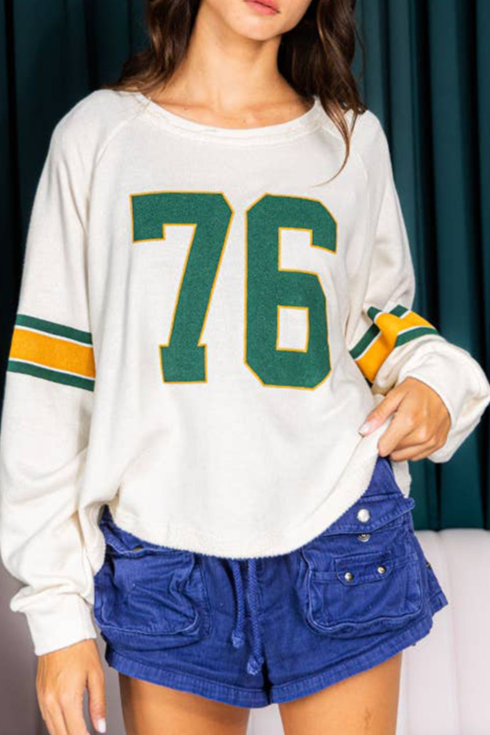 White raglan sleeve sweatshirt with green and gold '76' graphic and sleeve stripes