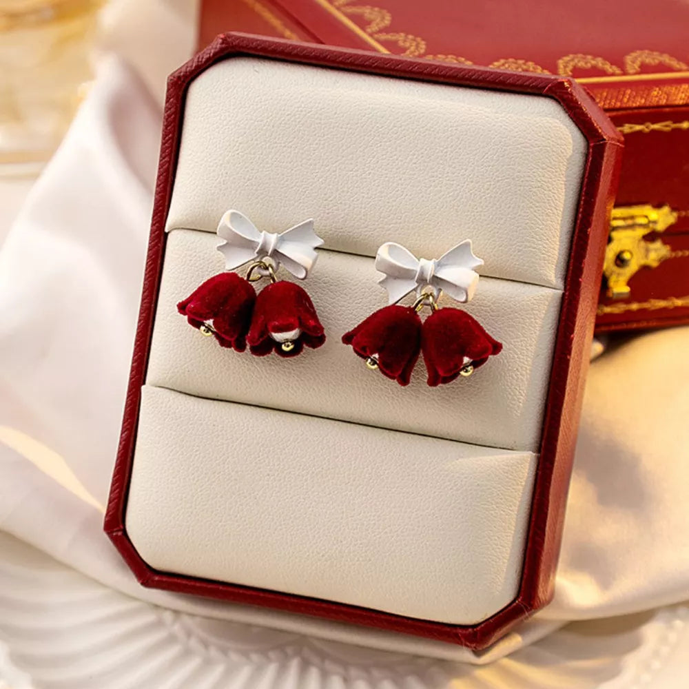 Velvet bell earrings in deep red with white bows and gold bead accents.