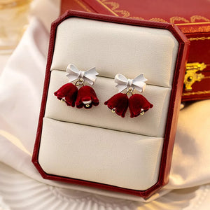 Velvet bell earrings in deep red with white bows and gold bead accents.