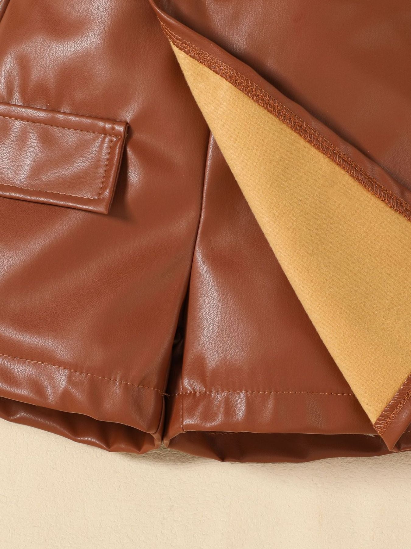 Brown faux leather baby shorts with pocket detail and soft lining.