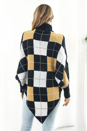 Geometric knit turtleneck cape in plaid pattern with black, white, and gold argyle design.