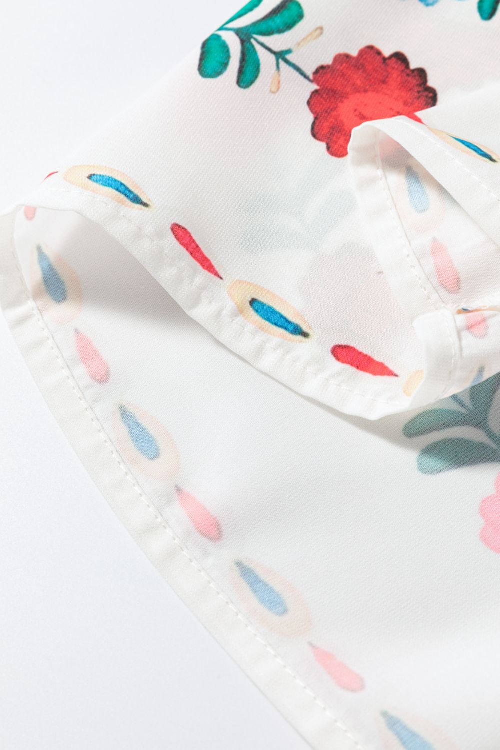 Embroidered medallion peplum blouse in floral print with ruffle detail and white fabric.