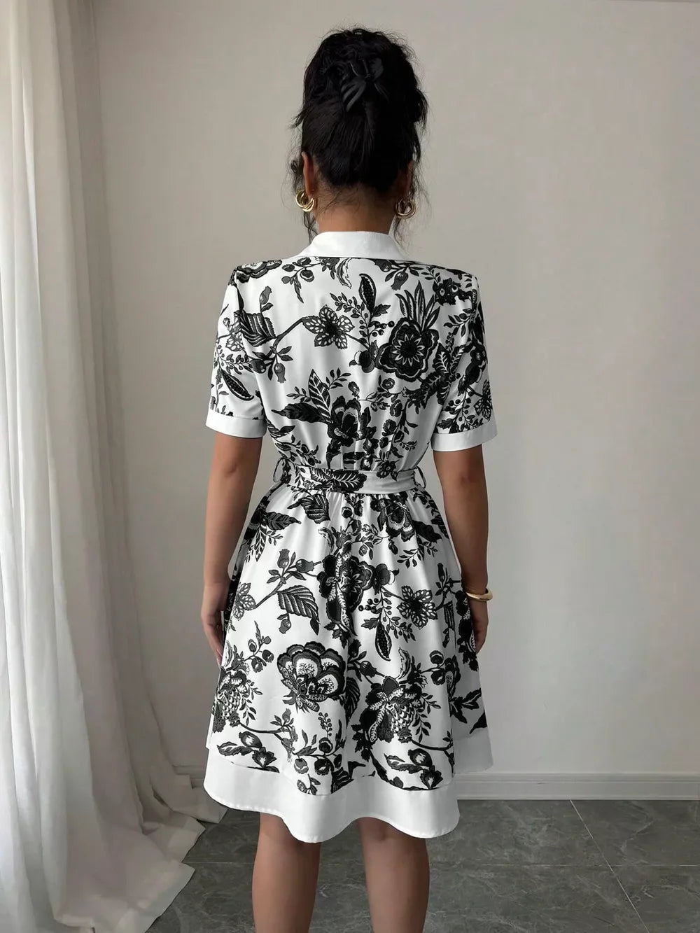 Floral print mini dress with tie belt, short sleeves, and collared neckline.