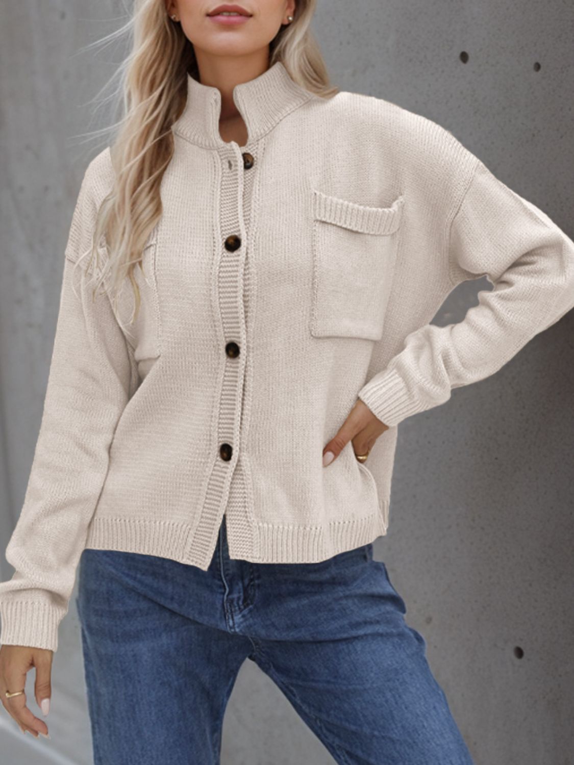 Cream stand collar knit cardigan with buttons and chest pockets.