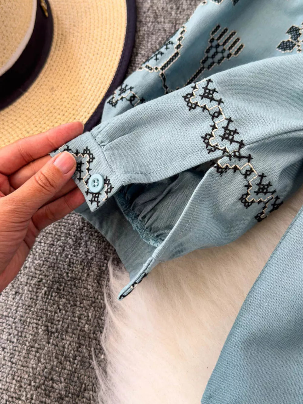 Light blue embroidered tie neck blouse with tassel detail on cuff.
