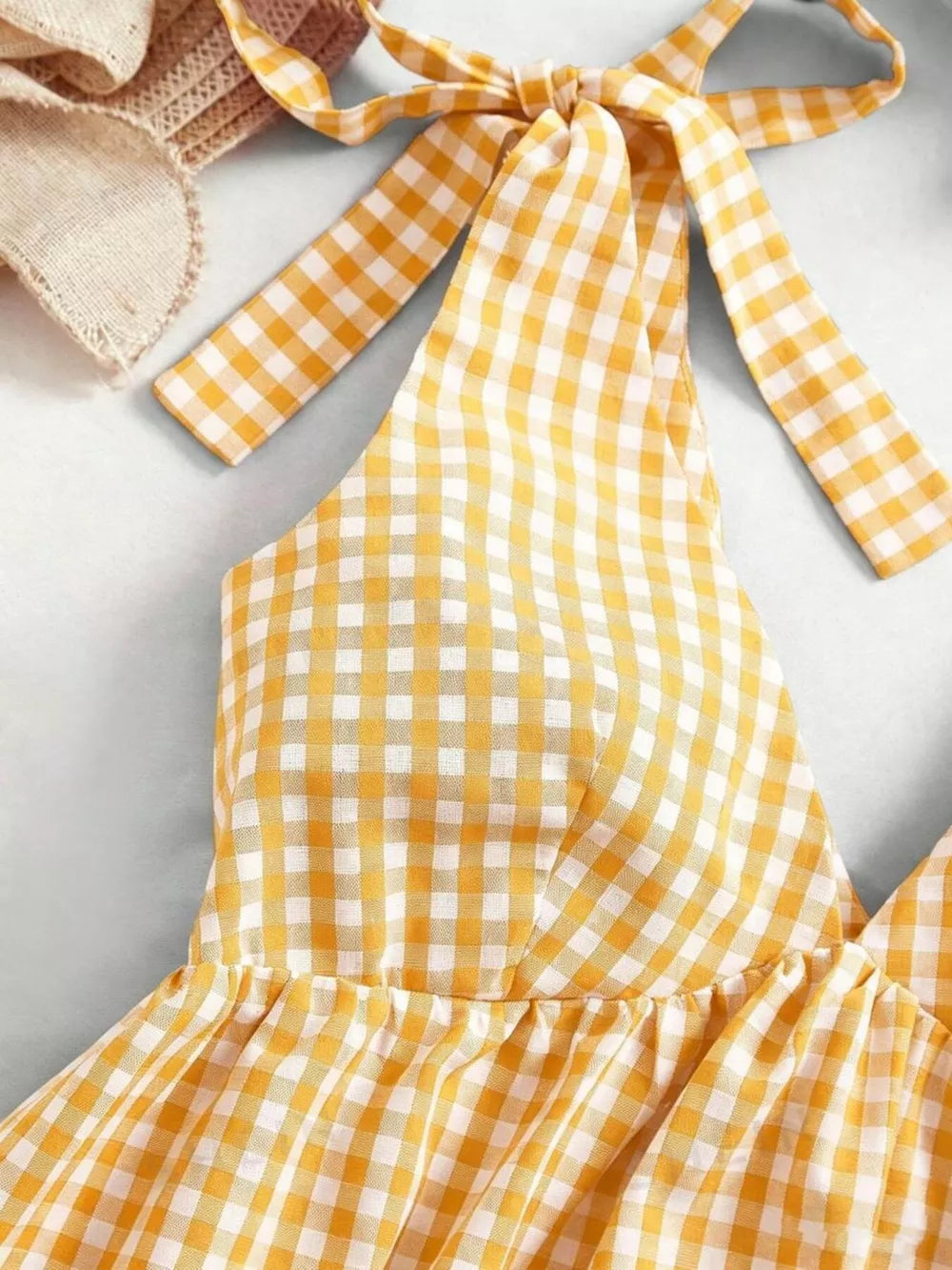 Yellow gingham mini dress with tie straps and ruffled hem detail.
