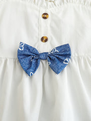 White cotton cami with sweetheart neckline, button front, and blue patterned bow detail.