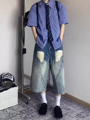 Relaxed fit distressed denim shorts with light wash and large distressed patches.