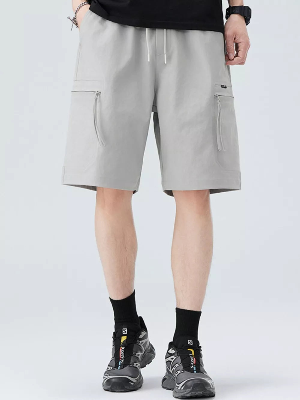 Men's light gray cargo shorts with zippered pockets and drawstring waist.