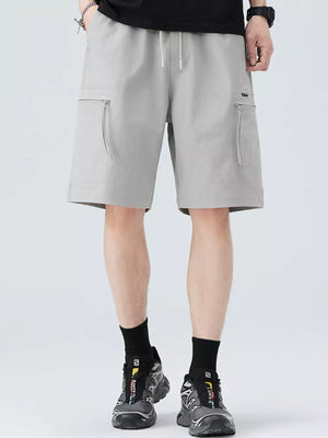 Men's light gray cargo shorts with zippered pockets and drawstring waist.