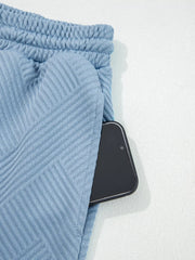 Light blue textured drawstring shorts with a phone in the pocket.