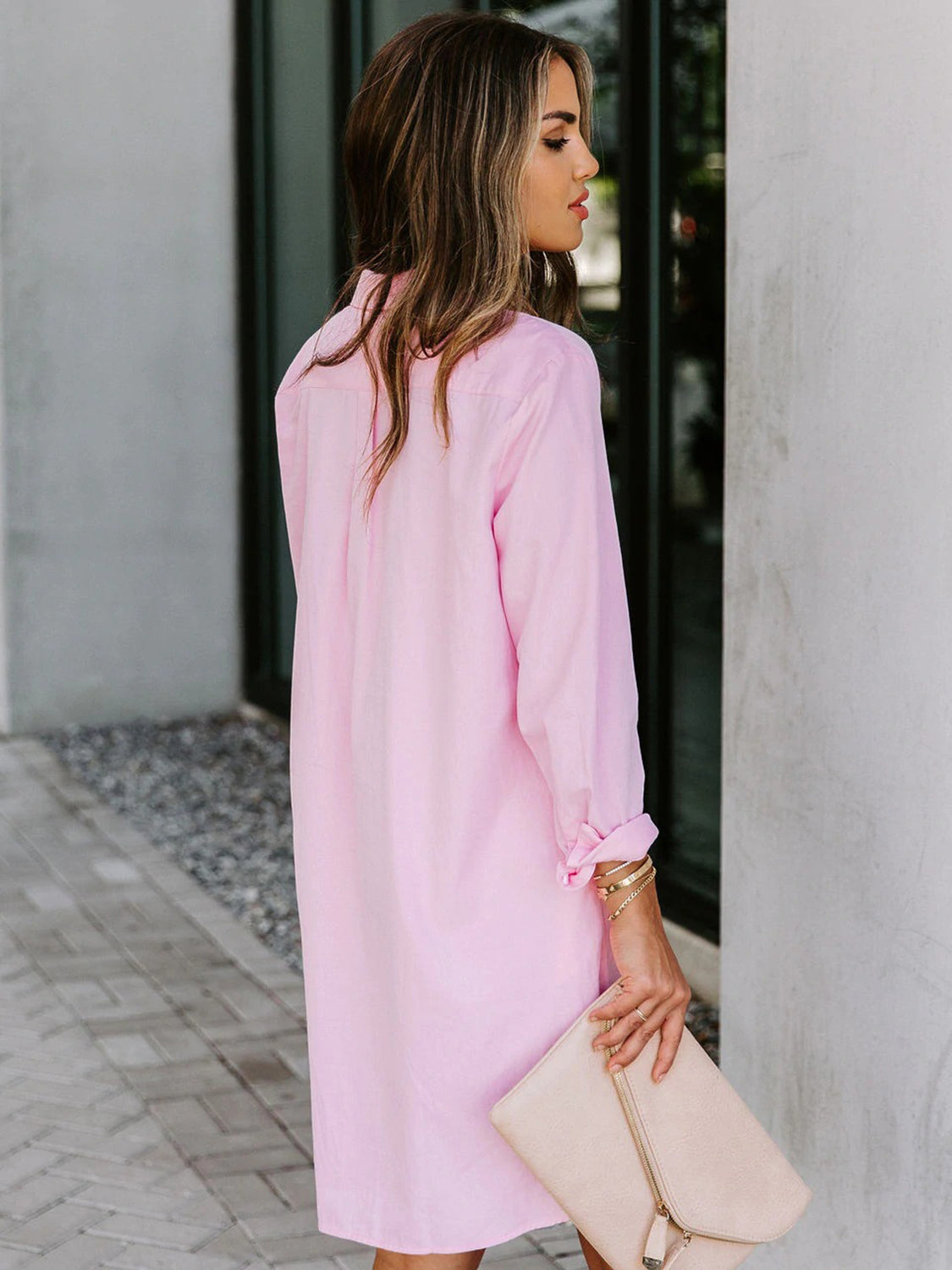 Oversized pink cotton shirt dress with button front and curved hem.