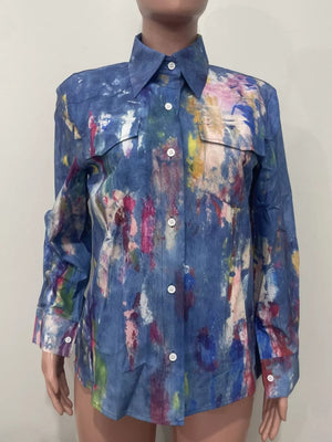 Denim button-up shirt with vibrant abstract paint splatter pattern, long sleeves, and two chest pockets.