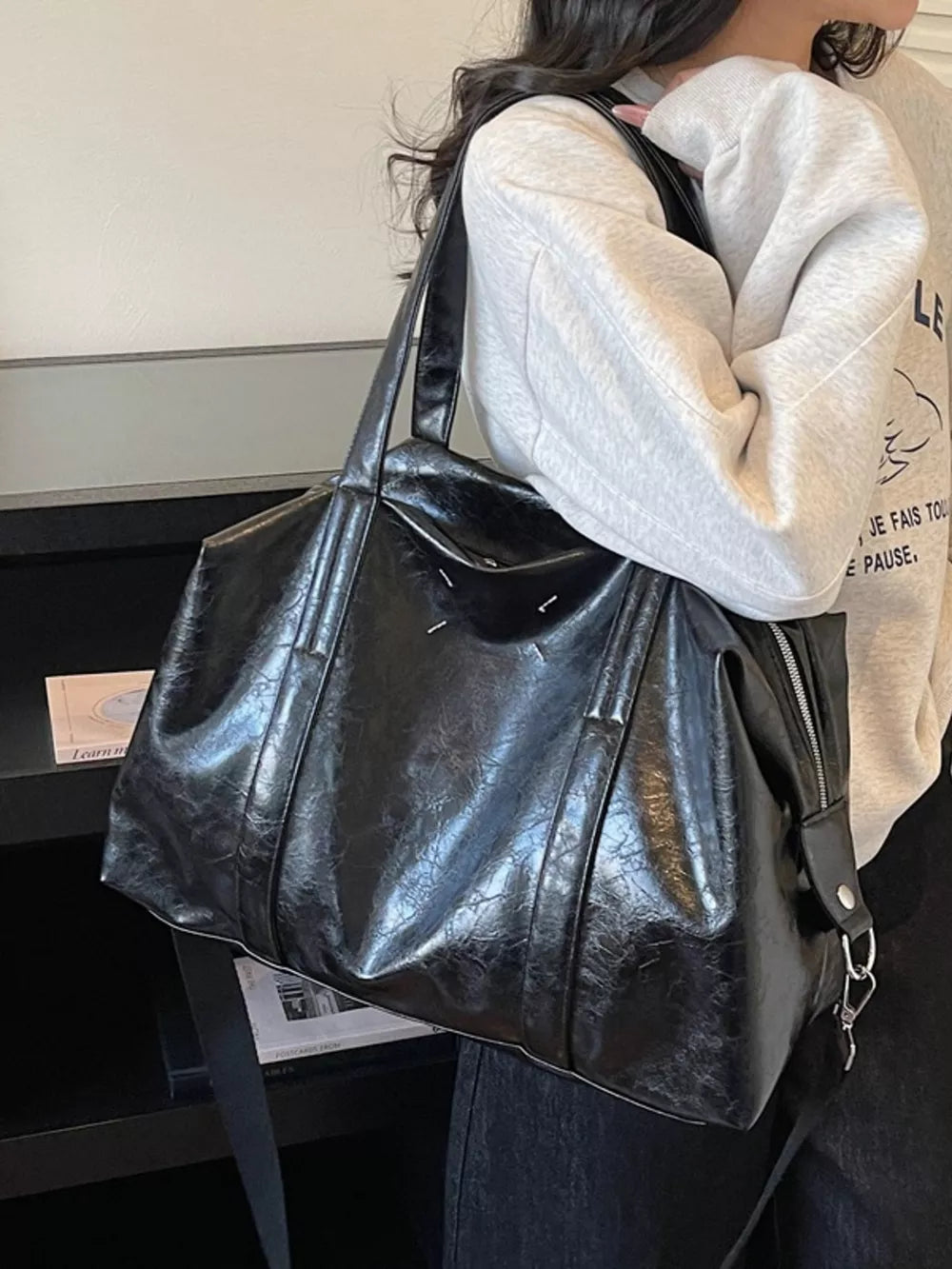 Black distressed vintage leather travel bag with zipper detail and silver hardware.
