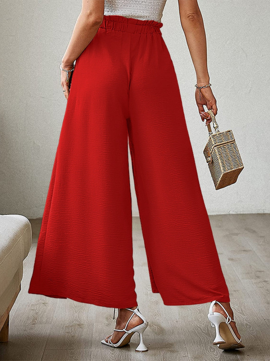 Red paperbag waist palazzo pants with side slits and a textured fabric.