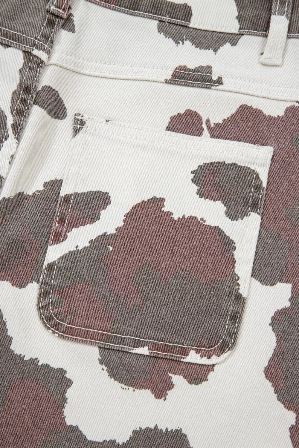 Cow print utility jeans with a visible cargo pocket detail.