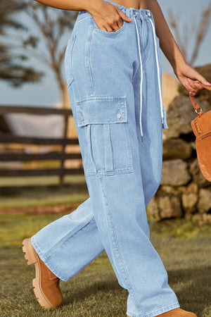 Light wash denim cargo pants with drawstring waist and pleated cargo pockets.