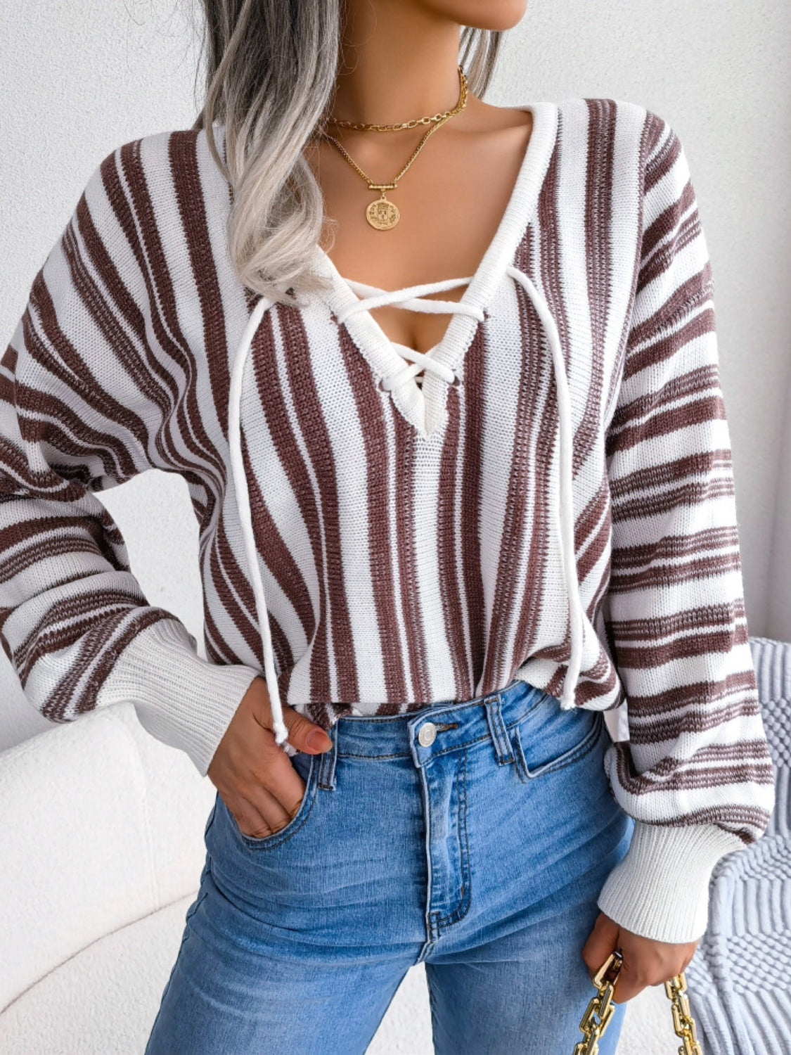 Brown and white striped knit pullover with lace-up neckline and long sleeves.