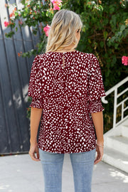 Burgundy blouse with white spot print, shirred short sleeves, and keyhole back detail.