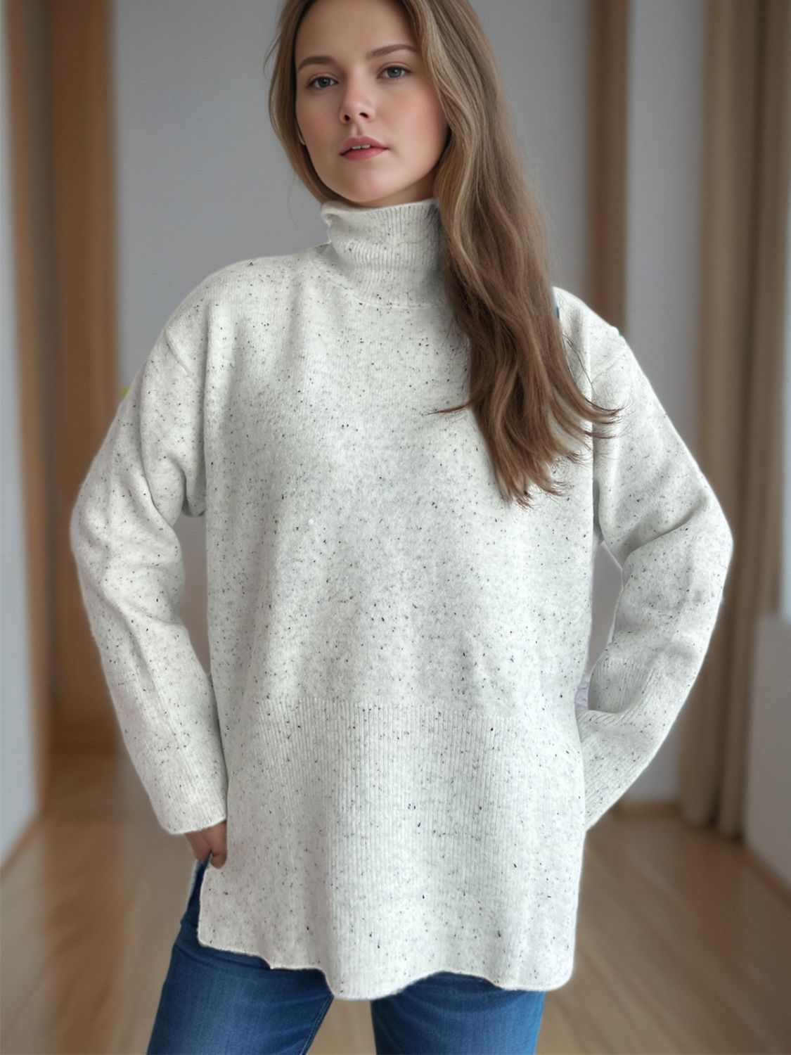 White speckled turtleneck sweater with ribbed hem and side slits.