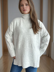White speckled turtleneck sweater with ribbed hem and side slits.