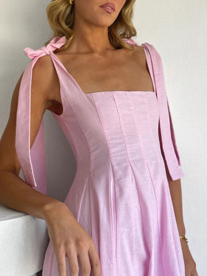 Pink bow-tie shoulder maxi dress with square neckline and pleated skirt detail.