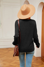Black relaxed knit sweater with lace trim and V-neck, styled with jeans and a hat.