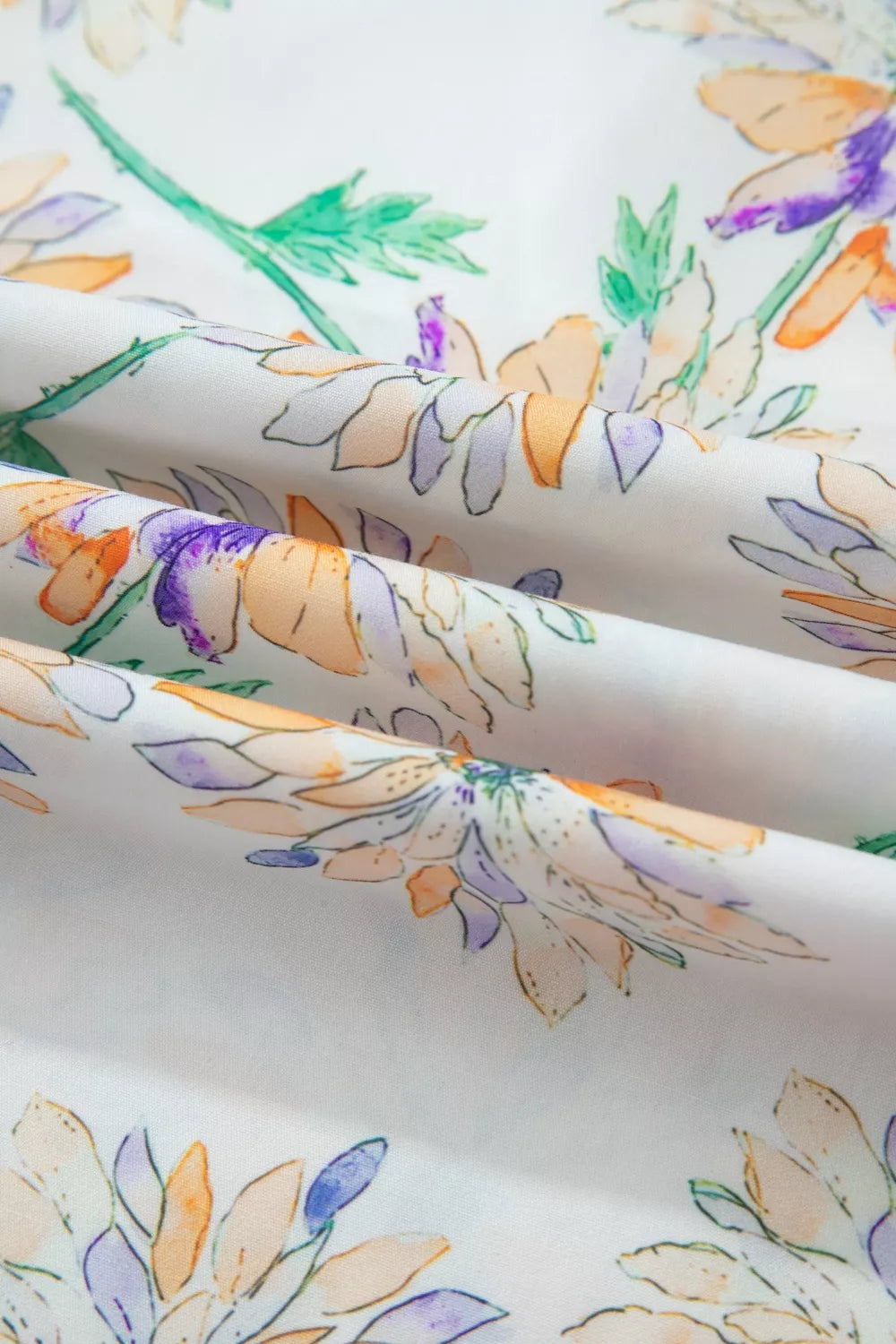 Floral print belted sleeveless dress fabric detail with watercolor flowers in orange, purple, and green on white.