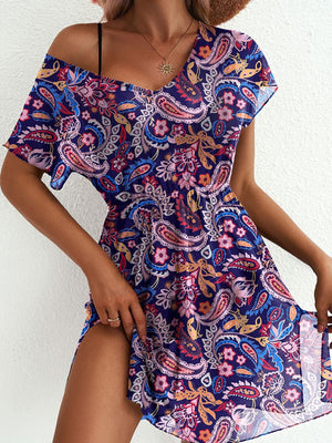 Vibrant leaf print mini dress in purple with a V-neck, short sleeves, and a thigh slit.
